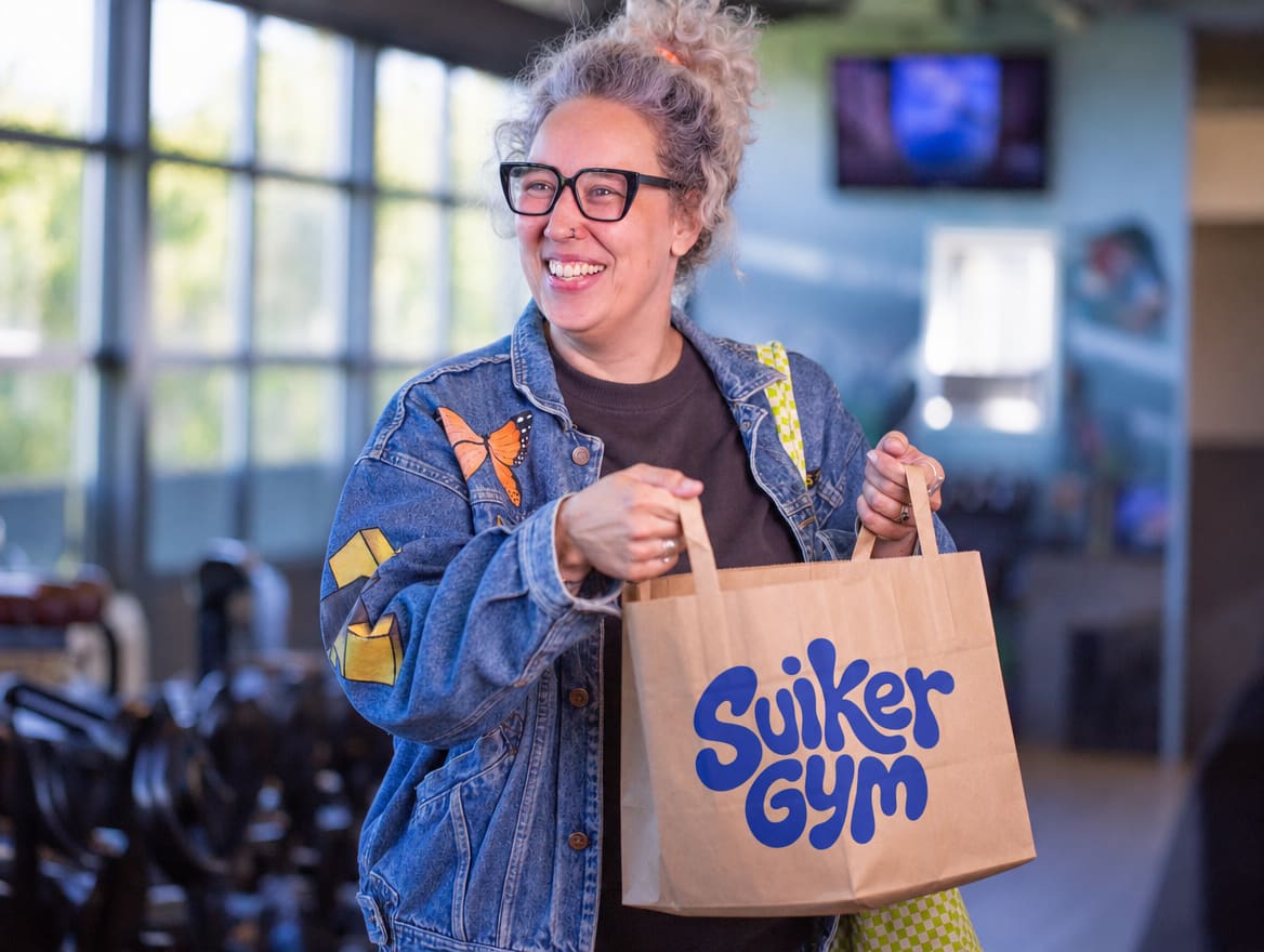 Een deelneemster verlaat de gym met haar ontbijt in een tas van Suikergym