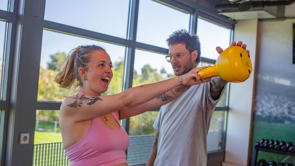 Elze begeleidt een deelnemer bij een oefening met een kettlebell